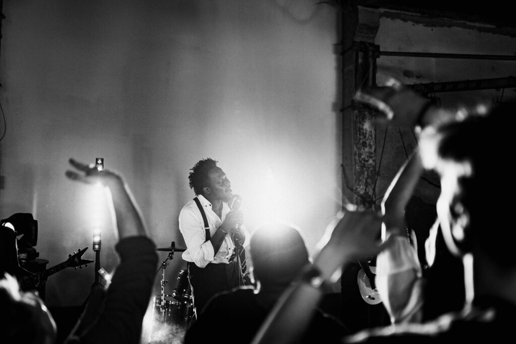 Energetic black and white photo of a singer performing on stage with a lively crowd.